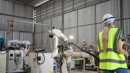 In robotic training instructor teach girl engineer to program robot arm look manual from laptop
