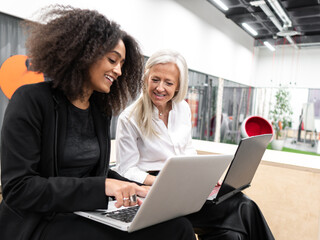 Smiling diverse female office workers using laptops at work