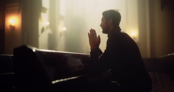 Young Christian Man Sits Piously in Majestic Church, with Folded Hands He Seeks Guidance From Faith and Spirituality while Praying. Religious Believer in the Great Power and Love of God. Slow Motion 