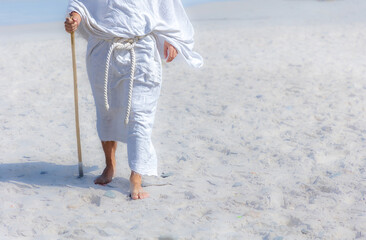 close up of a Biblical man in a white robe and staff walking in desert