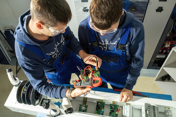 Technicians check motherboard with tester in equipped laboratory and solder cables. Electricians...