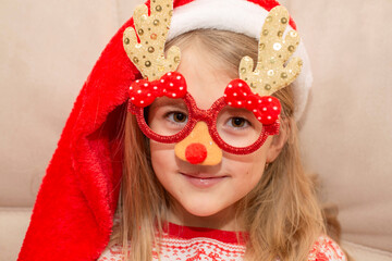 a girl in a Santa Claus hat and Christmas glasses in the form of Christmas trees
