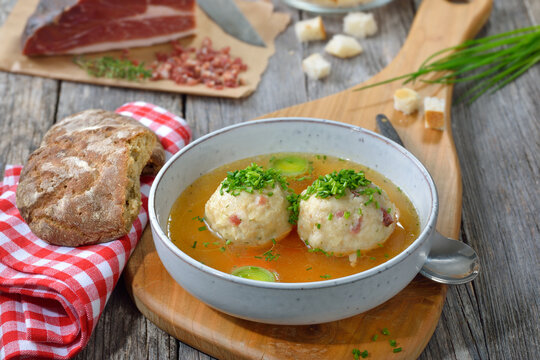 Kräftige Rinderbrühe mit Südtiroler Speckknödeln rustikal serviert – Delicious South Tyrolean bacon dumplings soup with hot beef broth and chives