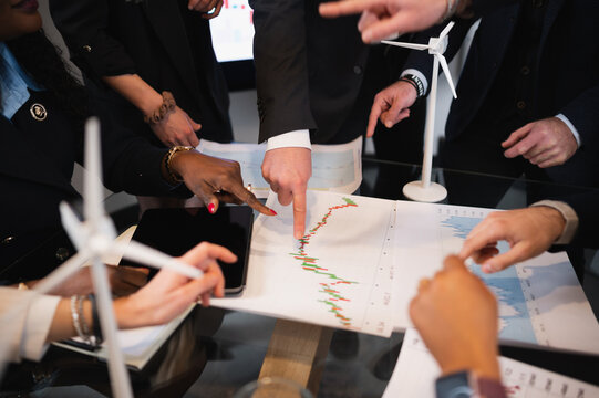 Unrecognizable businesspeople pointing something on a graph or gesturing. Creative idea teamwork.