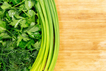 Fresh organic raw greenery. Parsley, dill, cilantro and green onion on wooden kitchen board with copy space. Vegan, vegetarian and healthy food concept. Closeup, flat lay