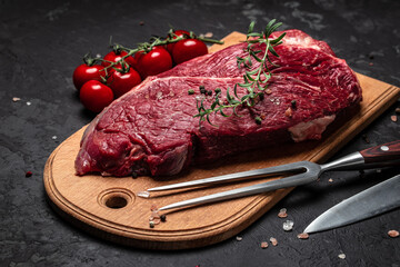 Fresh and raw beef meat. Whole piece of tenderloin with steaks and spices ready to cook on dark background, banner, menu, recipe place for text, top view