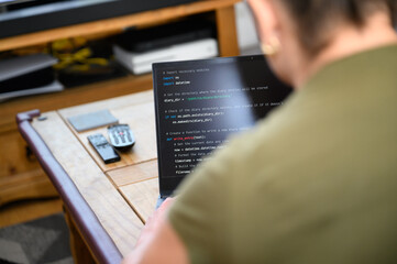 Coding in the house, a woman writing code on a laptop for an app or website while working from home