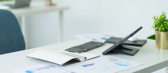 Tablet computer and business chart paper on desk for advertising and text.