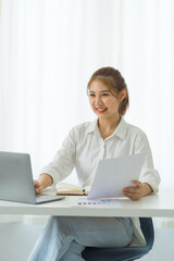 Attractive asia employees in successful modern office university education Financial graphs on her workstation. Young asian freelance employee online marketing ecommerce telemarketing concept report