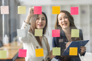 Team of Business female employee with many conflicting priorities arranging sticky notes commenting...
