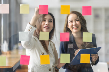 Team of Business female employee with many conflicting priorities arranging sticky notes commenting...