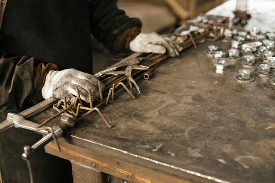 Unrecognizable man’s hands on clamp, rods and pliers gathered together