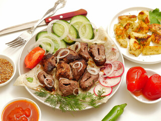 Georgian cuisine. Lamb barbecue. Fresh vegetables, Shoti bread. Potatoes in a rustic way. On a white background. 