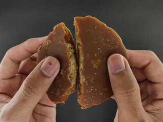 Palm sugar. coconut sugar or palm sugar, split. kitchen seasoning, sweet taste enhancer. with the concept of being held by hand. on a black background, on black paper. seen from above.