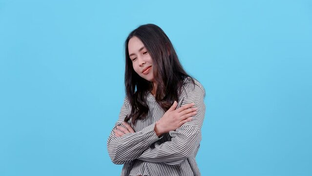 4K, portrait, Woman with long hair wearing striped shirt, He stroked his hands, both upper arms, gently, Relieve the very cold weather right now, Isolated indoor studio on blue background.