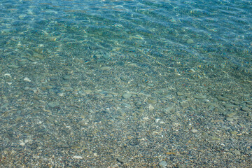 Fototapeta na wymiar Texture of turquoise sea water with stones