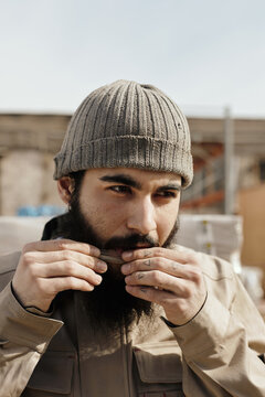 Portrait of young worker licking edge of paper to seal hand-rolled cigarette