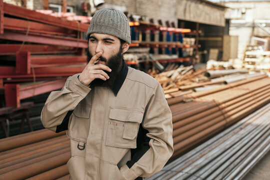 Horizontal waist up shot of young male metalworker smoking cigarette during break