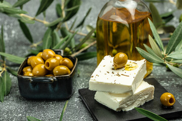 Green olives with feta cheese and young olives branch on dark background. top view. place for text