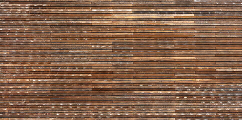 Verwitterte Holzwand aus vielen schmalen horizontalen Brettern in verschiedenen braunen Farbtönen
