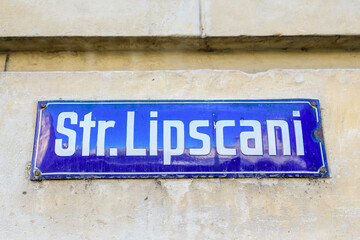 Beautiful vintage street sign showing Strada Lipscani (Lipscani Street) displayed on an street in the old city center of Bucharest, Romania, in a sunny day with clear blue sky