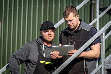 Vernetzt: Landwirt und sein Sohn blicken auf das Ipad und sehen die Daten von ihrer Biogasanlage,...