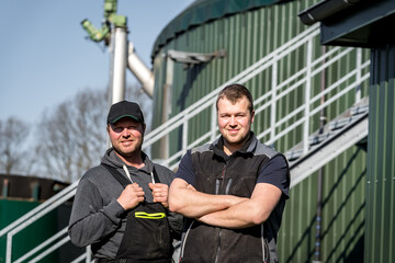 Zwei Landwirte stehen zufrieden vor ihrer Biogasanlage.