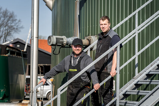 Zwei Landwirte gehen nacheinander die Treppe der Biogasanlage hinab.