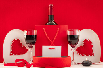 Fond d'écran avec des cœurs rouges pour la Saint-Valentin avec un paquet cadeau et du vin rouge....