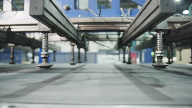Modern production equipment at factory. Automated transportation of products. Manipulator with vacuum suction cups above conveyor line closeup