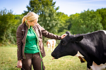  Ausbildungsberuf Landwirtschaft; Hübsche Auszubildende auf einer Weide mit einer Kuh.
