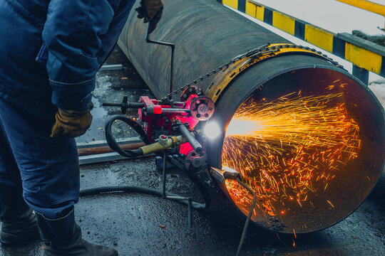 Working welder cuts metal and sparks fly. Gas cutting of large diameter pipes with acetylene and oxygen. Industrial metal cutting in oil and gas industry.