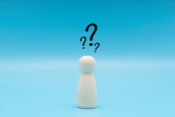 Wooden human figurine with a question mark. Minimalism. Asking a question, searching for truth and...