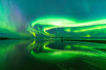 Northern lights reflected in water. Person standing on the bech. Storsand, Jakobstad/Pietarsaari...