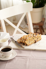 Traditional german christmas pastry stollen on a marble cutting board, coffee mug, butter plate on...