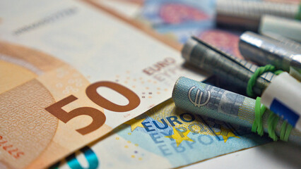 Close up of a fifty euro bill and a roll of a five euro bill where you can see the euro sign with a small focus area