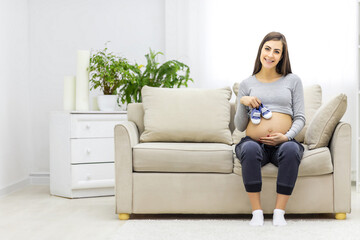Fototapeta premium Photo of pregnant woman with naked stomach and child clothes.