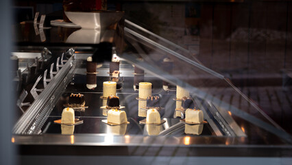 Cakes displayed in the showcase of the pastry shop. Chocolate in a showcase. Confectionery shop wallpaper background. Glass showcase chocolate