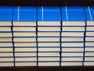 A stack of identical church books with blue covers with cross on a shelf in a church