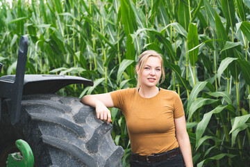 Junge Landwirtin hält mit dem Trecker, an gut gewachsene Maispflanzen.