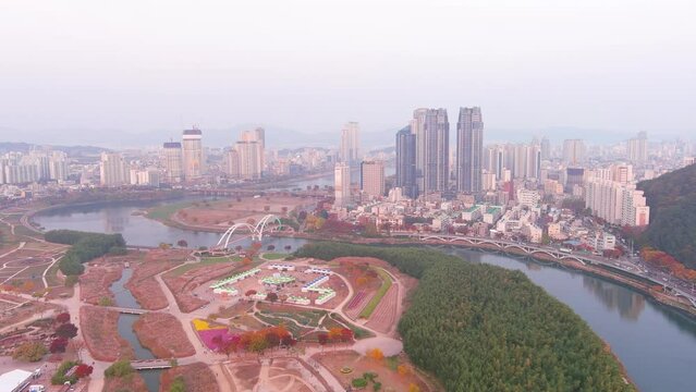 Ulsan: Aerial view of city in South Korea, modern high-rise buildings (skyscrapers) at sunset, trees in autumn colors, Taehwagang National Garden - landscape panorama of Eastern Asia from above