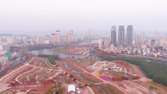 Ulsan: Aerial view of city in South Korea, modern high-rise buildings (skyscrapers) at sunset, trees in autumn colors, Taehwagang National Garden - landscape panorama of Eastern Asia from above