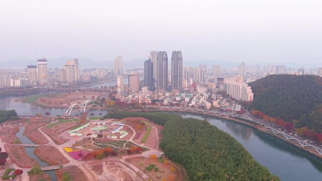 Ulsan: Aerial view of city in South Korea, modern high-rise buildings (skyscrapers) at sunset, trees in autumn colors, Taehwagang National Garden - landscape panorama of Eastern Asia from above