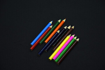 Colored pencils on a black background. Small pencils close-up.