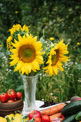 a bouquet of sunflowers on a table with an autumn harvest of vegetables and fruits