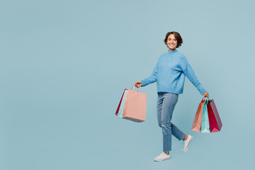 Full body sideways young woman wears casual clothes hold in hand paper package bags after shopping...