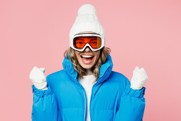 Snowboarder happy fun woman in blue suit goggles mask hat ski padded jacket do winner gesture celebrate isolated on plain pastel pink background Winter extreme sport hobby weekend trip relax concept