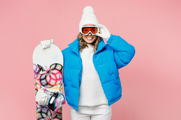Snowboarder woman wear blue suit goggles mask hat ski padded jacket hold glasses snowboard look...