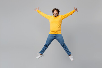 Full body excited fun cool happy young Indian man 20s he wearing casual yellow hoody jump high with...