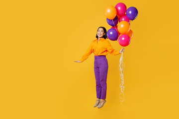 Fototapeta na wymiar Full body side view fun happy young woman wearing casual clothes hat celebrating hold bunch of balloons jump pov flying in air isolated on plain yellow background. Birthday 8 14 holiday party concept